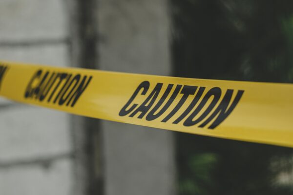 Close-up view of yellow caution tape creating a warning barrier outdoors.